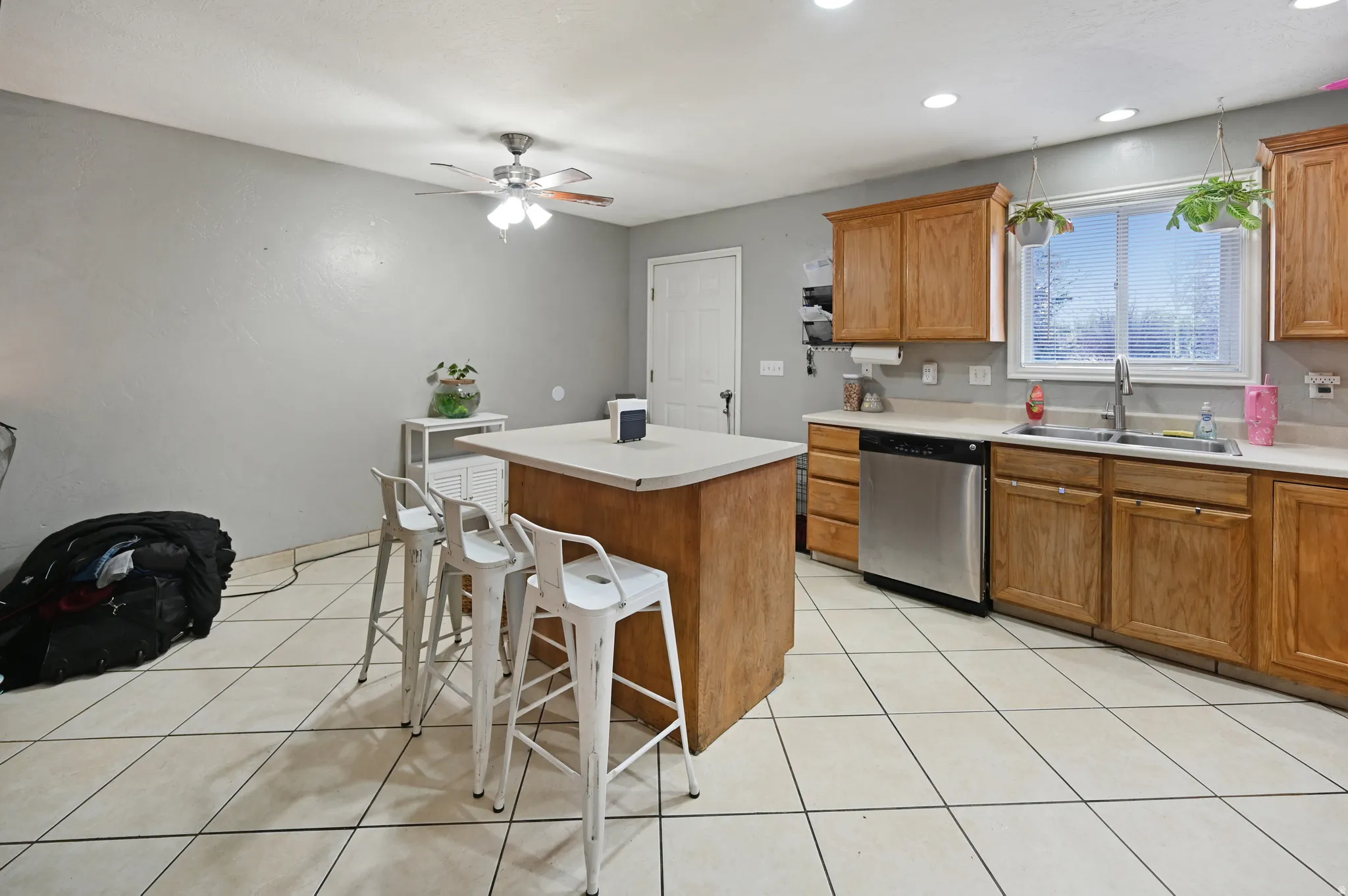 Kitchen featuring wood finish cabinets, light countertops, dishwasher, a kitchen island, and light tile patterned floors