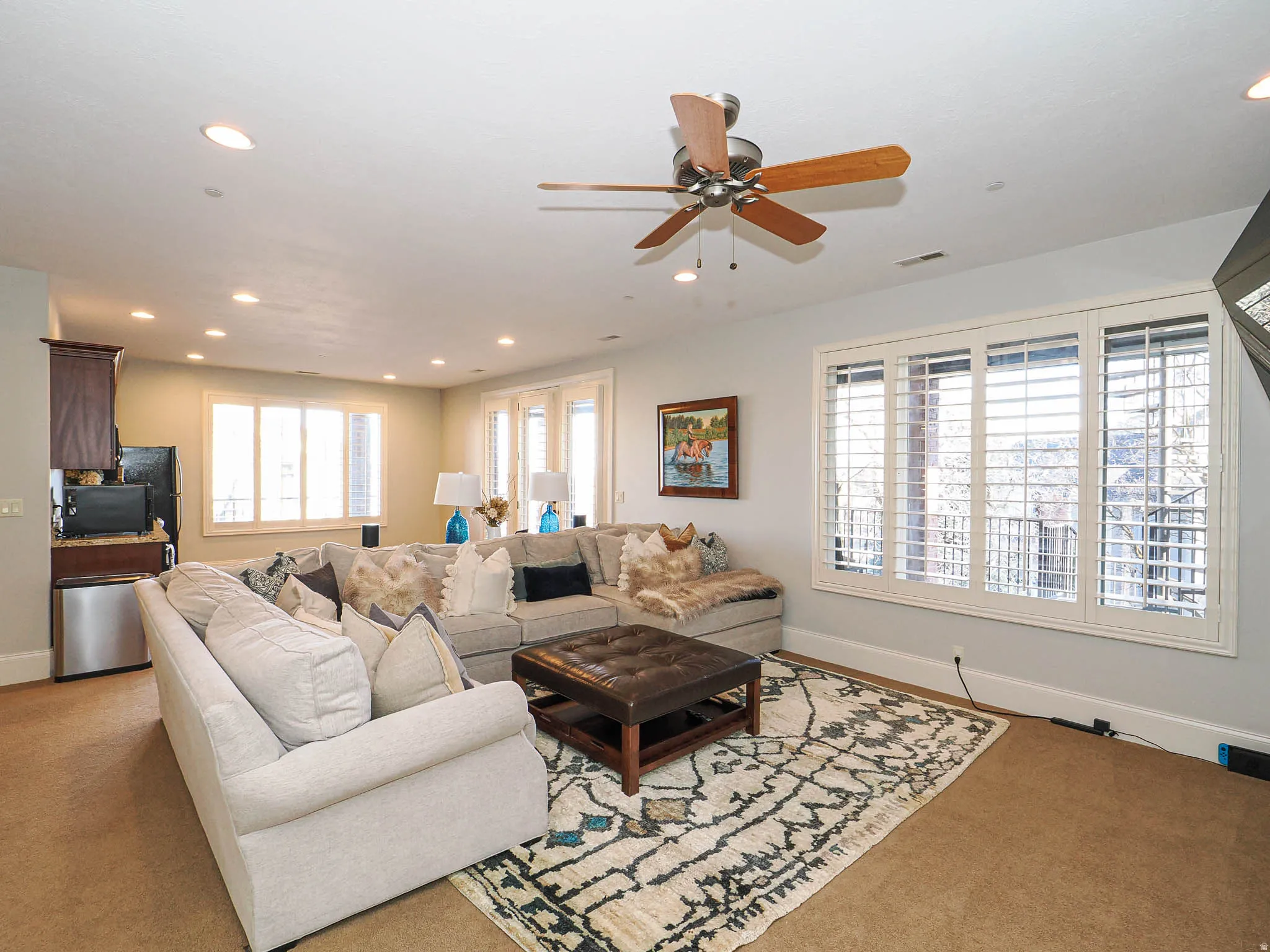 Carpeted living room with ceiling fan and recessed lighting
