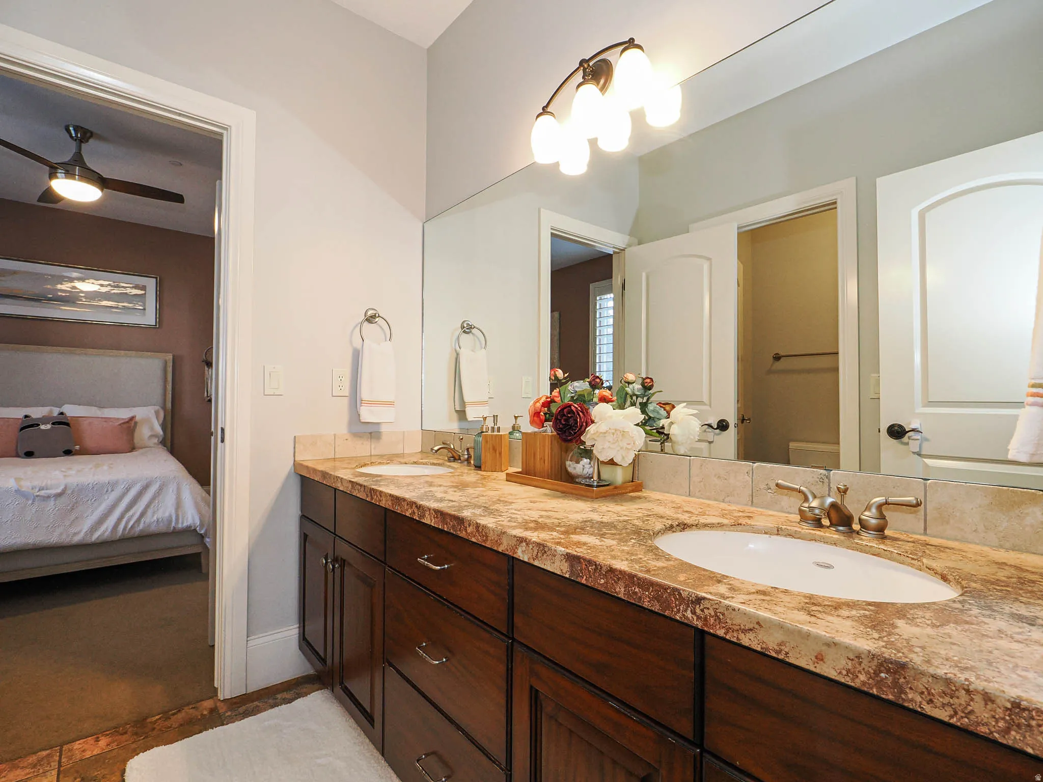 Full bathroom featuring double vanity, ensuite bath, and ceiling fan