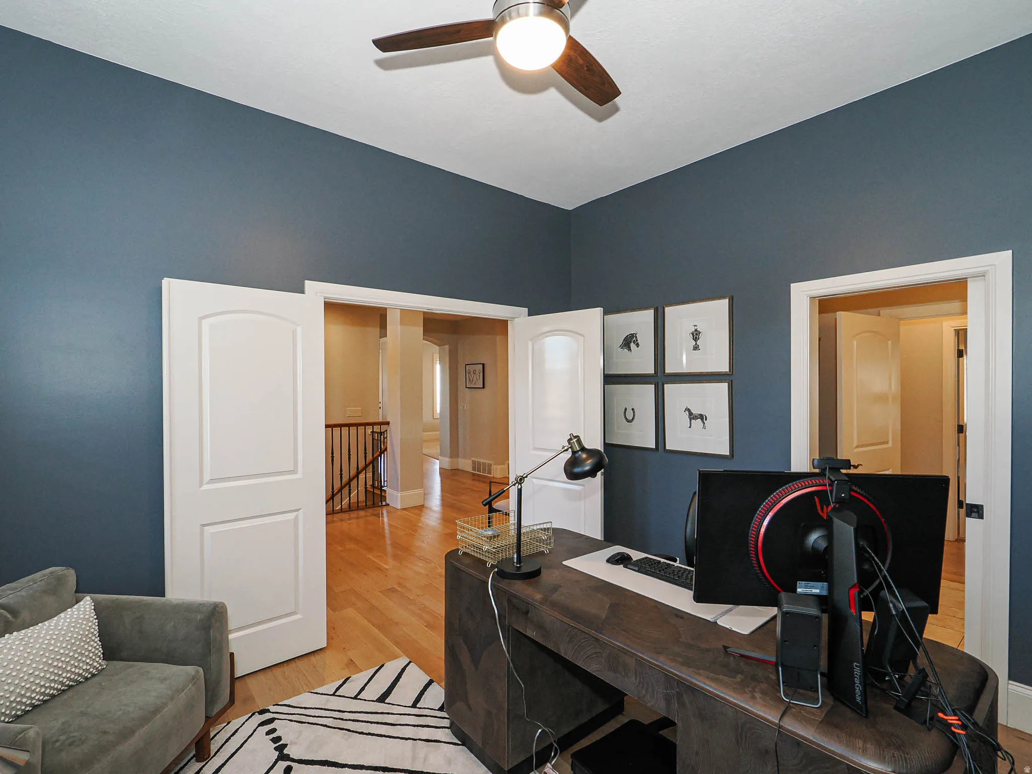 Office area with light wood finished floors and a ceiling fan