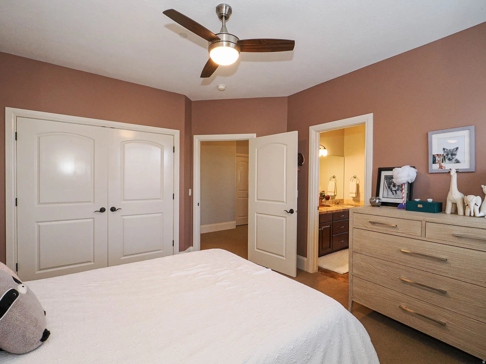 Bedroom with dark colored carpet, a ceiling fan, a closet, and ensuite bathroom