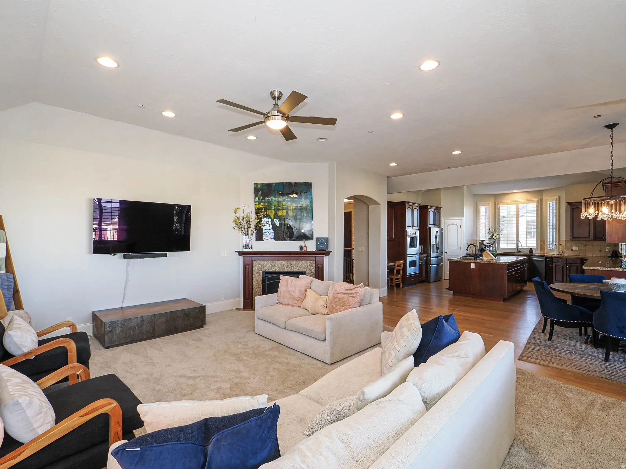 Living area featuring a fireplace, a chandelier, ceiling fan, arched walkways, and light wood-style floors