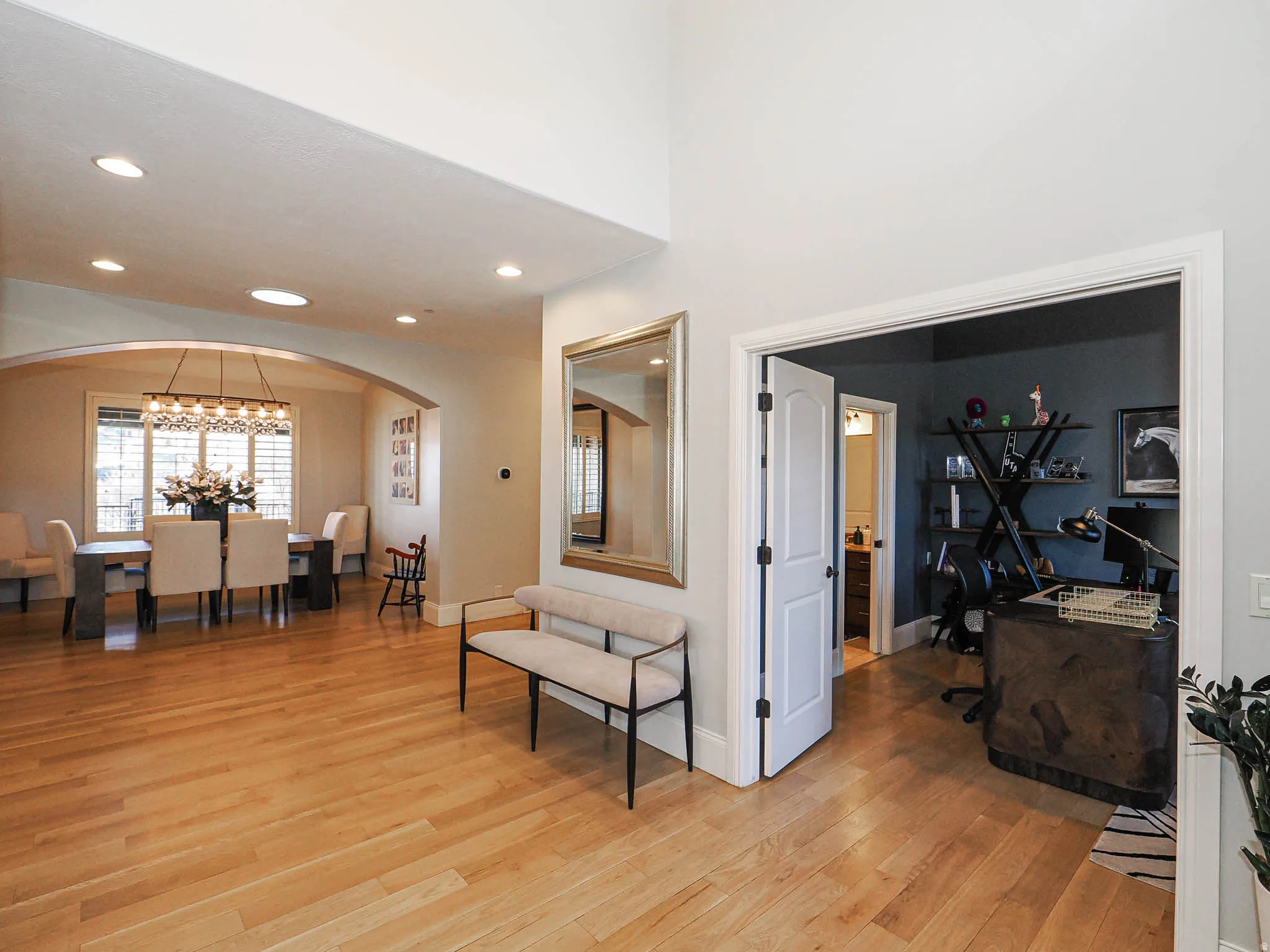 Entrance foyer with light wood-style floors, arched walkways, and a chandelier
