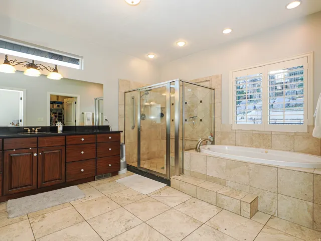 Bathroom with a walk in closet, a stall shower, a bath, vanity, and light tile patterned floors
