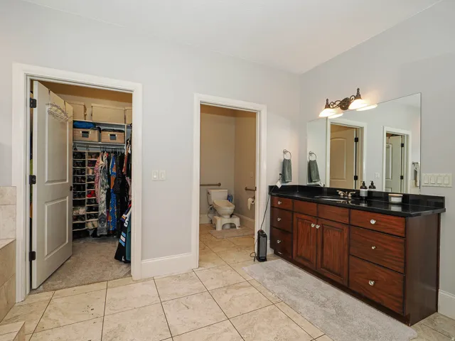 Bathroom with vanity, light tile patterned floors, and a walk in closet