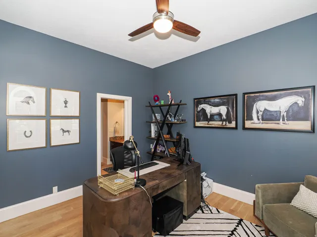Home office with light wood-type flooring and a ceiling fan