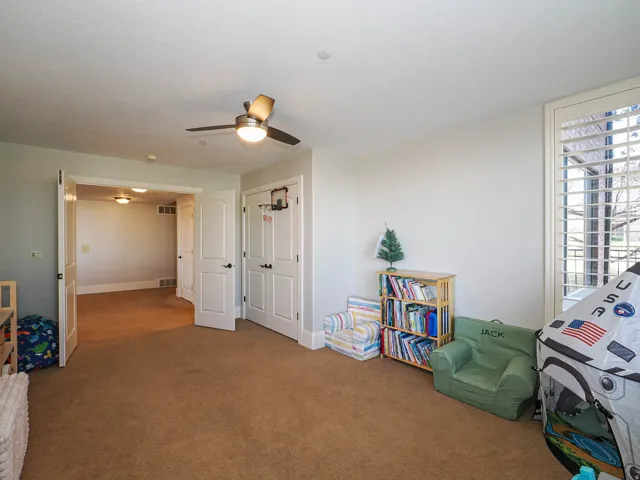 Game room with a ceiling fan and carpet flooring