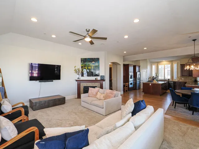 Living area featuring a fireplace, a chandelier, ceiling fan, arched walkways, and light wood-style floors