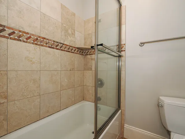 Bathroom featuring toilet and combined bath / shower with glass door