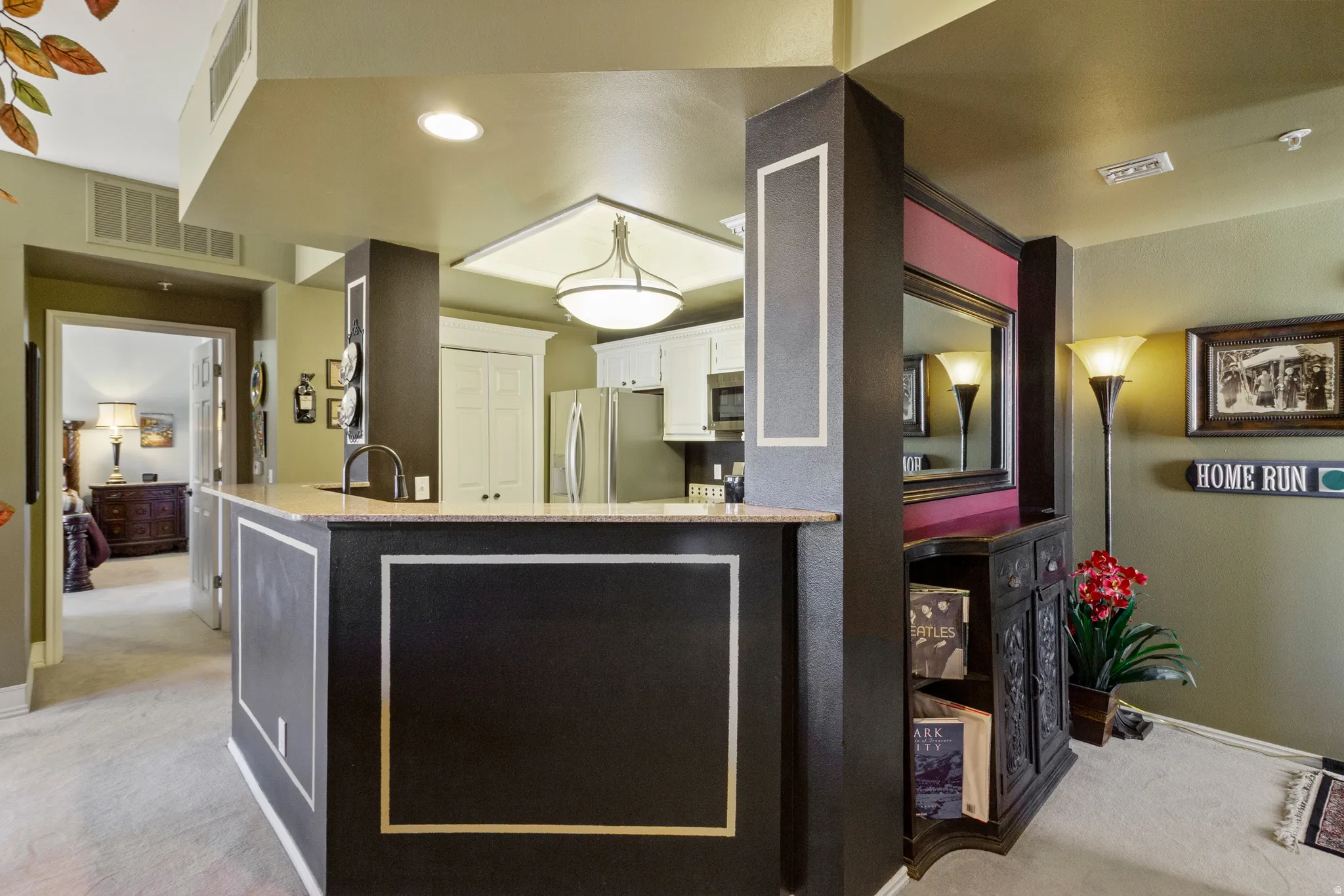 Kitchen featuring light colored carpet, white cabinetry, light stone countertops, stainless steel appliances, and a peninsula