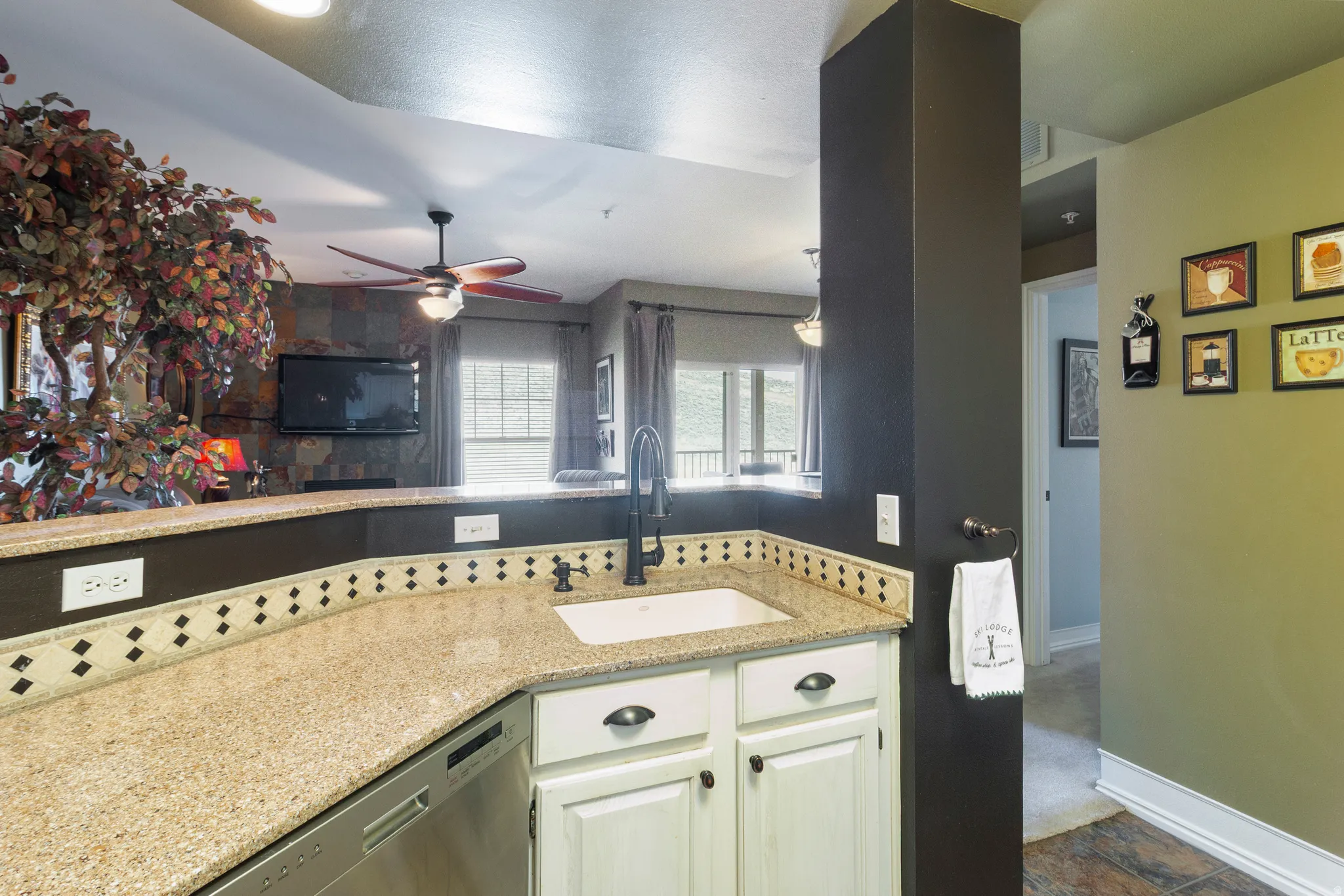 Kitchen with light stone counters, dishwasher, a ceiling fan, and white cabinets