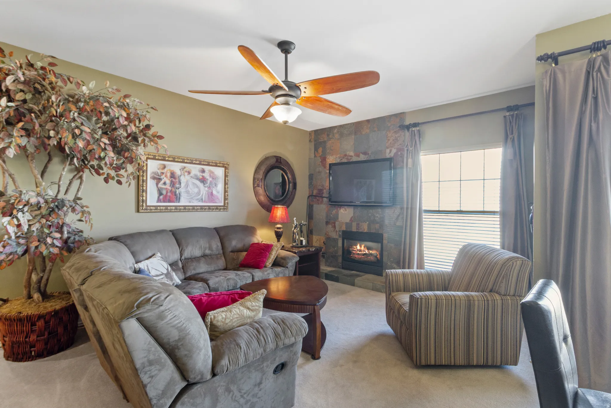 Living area with carpet floors, a ceiling fan, and a tile fireplace