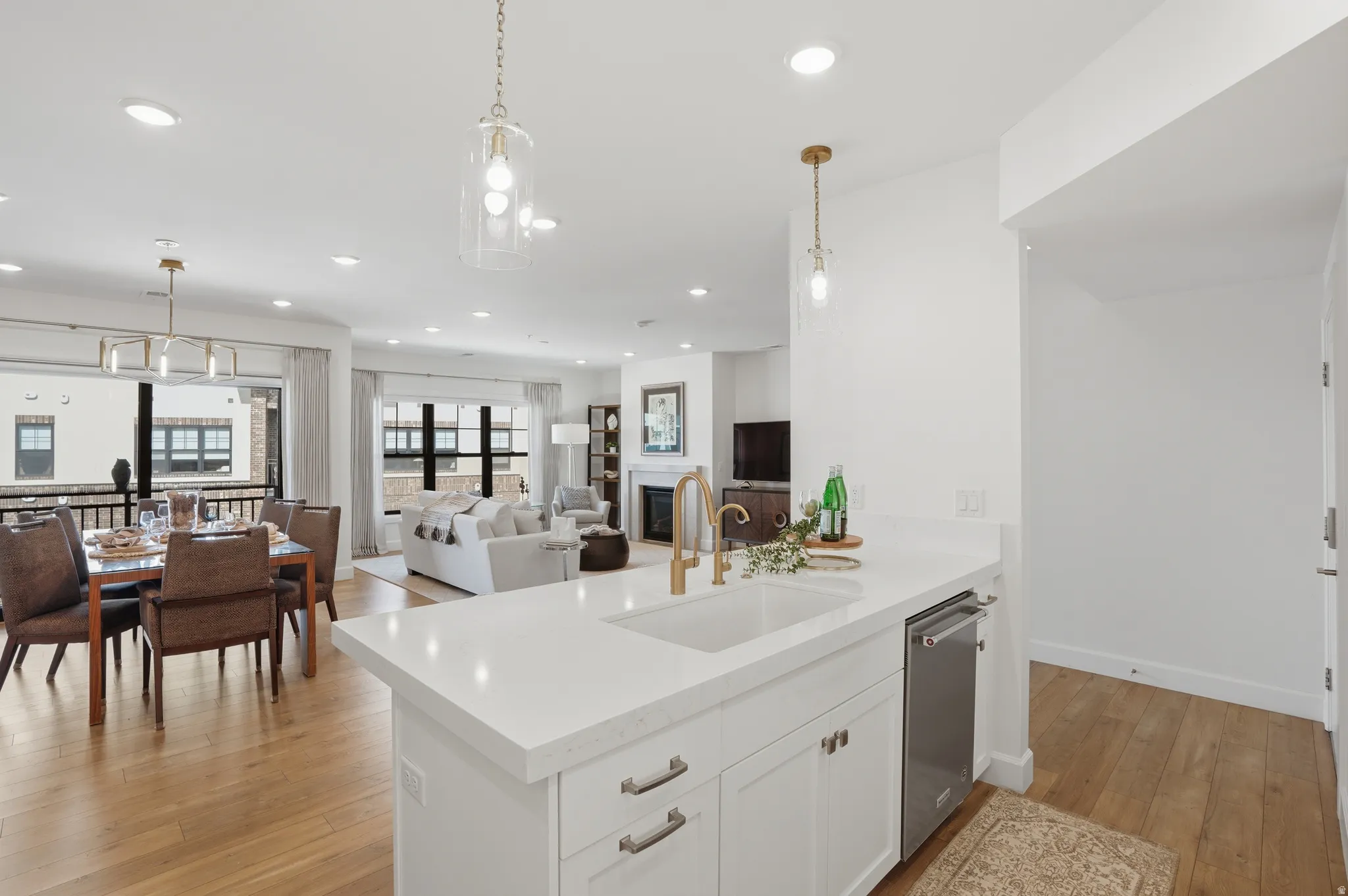 Kitchen with decorative light fixtures, white cabinetry, light wood-style flooring, and a glass covered fireplace