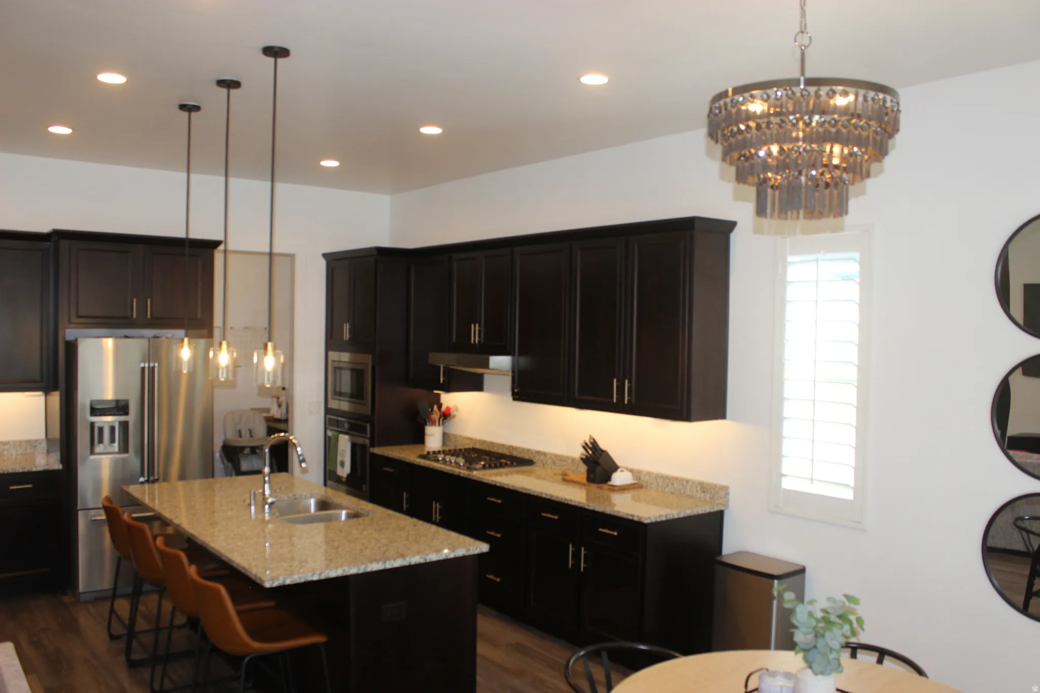 Kitchen featuring light stone countertops, stainless steel appliances, hanging lights, an island with sink, and a breakfast bar