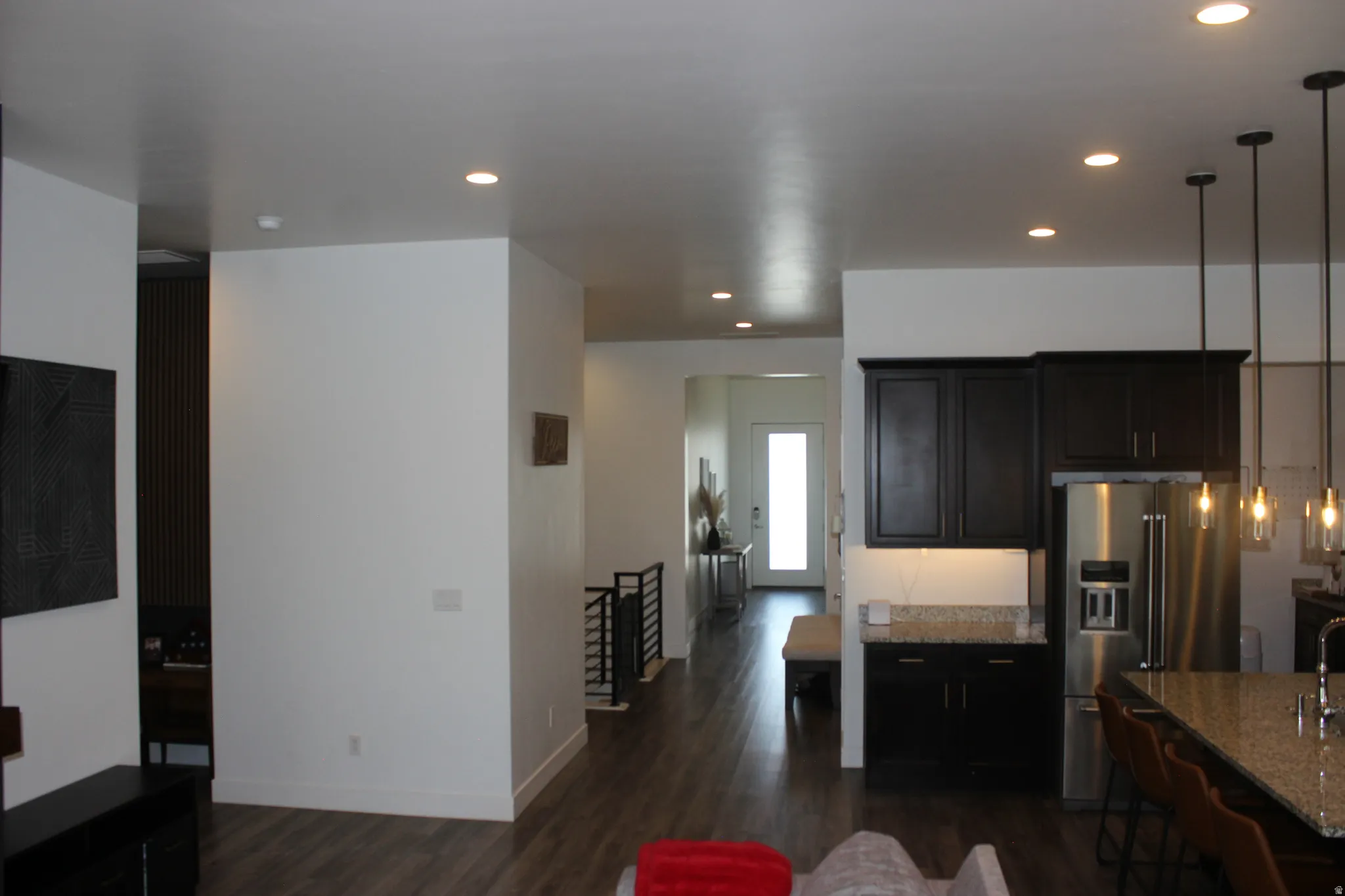 Kitchen featuring pendant lighting, high quality fridge, dark wood-type flooring, light stone countertops, and dark cabinets