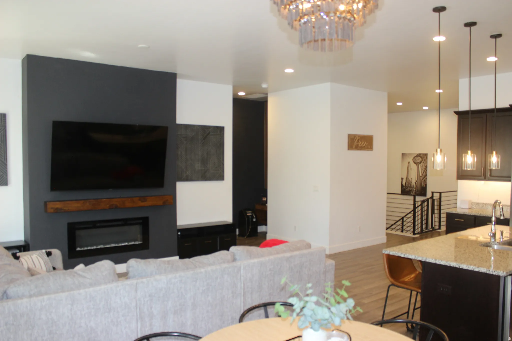 Living area with light wood finished floors, suspended lighting, and a glass covered fireplace