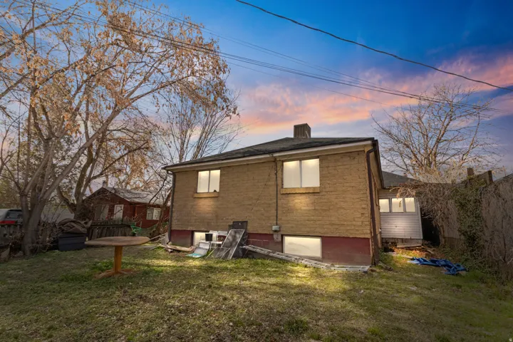 Rear view of house featuring a lawn and brick siding