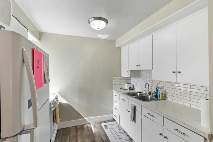 Kitchen featuring white appliances, white cabinets, light countertops, dark wood-type flooring, and a textured ceiling