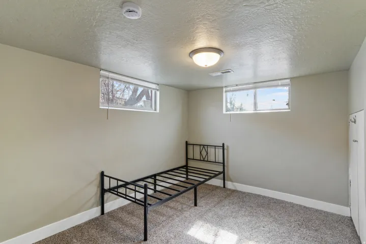 Unfurnished bedroom with light carpet, a textured ceiling, and multiple windows
