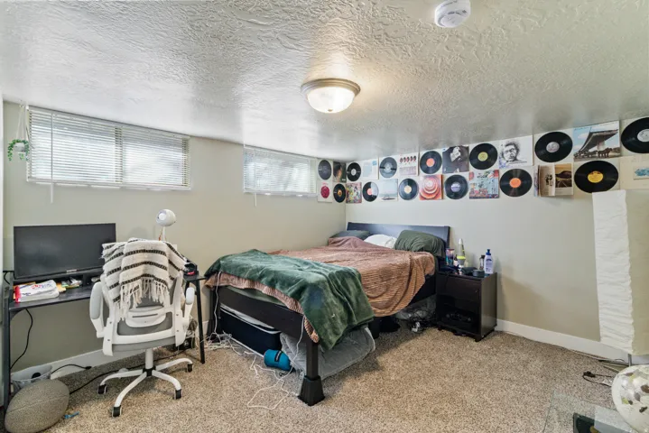 Bedroom with a textured ceiling, light carpet, and an office area