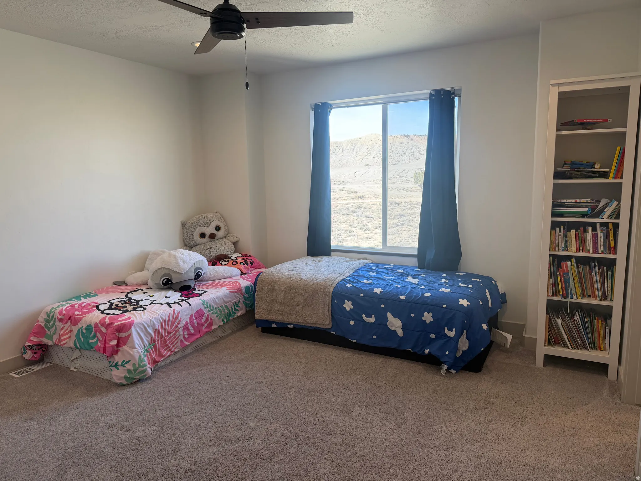 Bedroom with a textured ceiling, carpet floors, and a ceiling fan