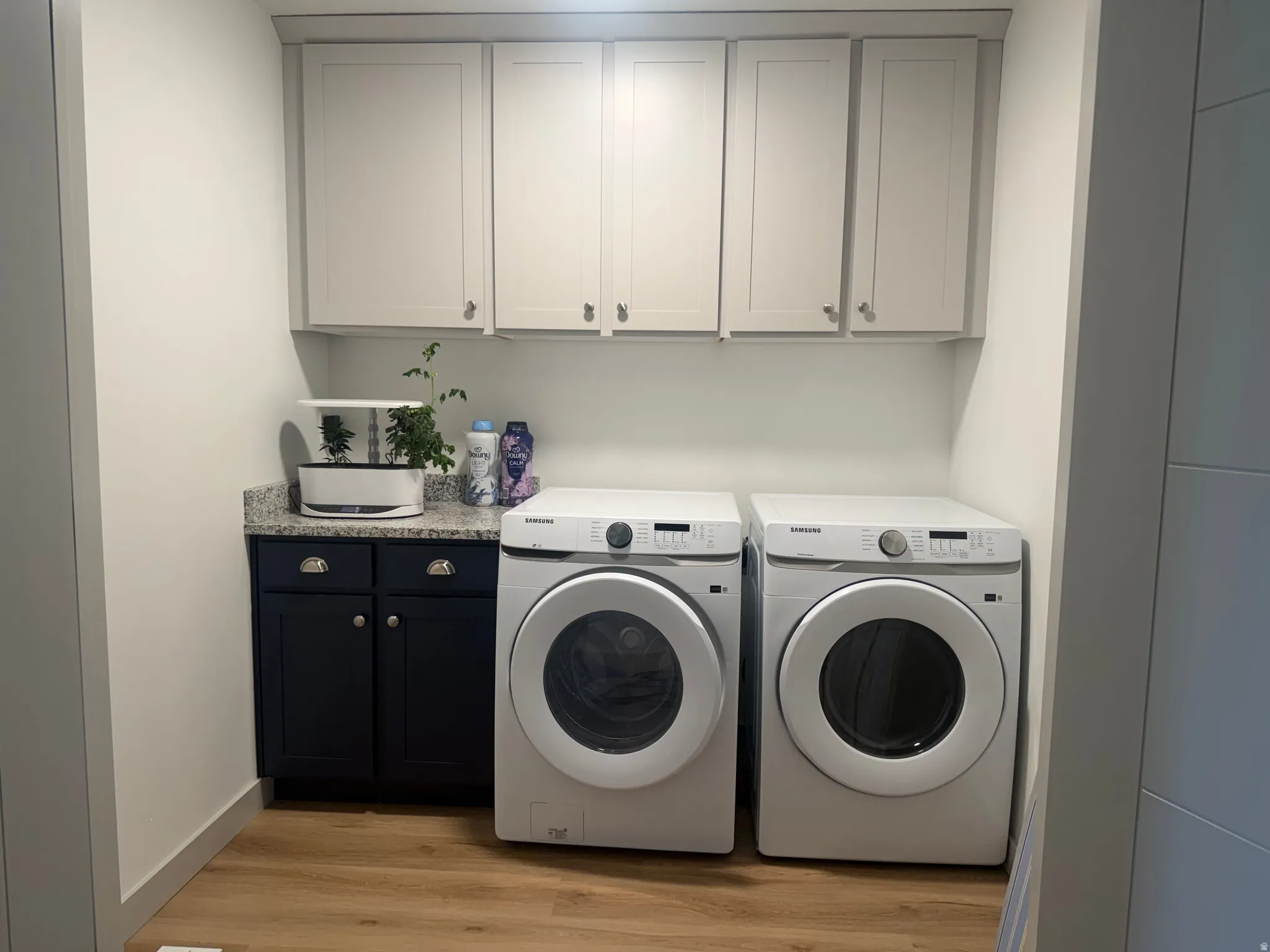 Laundry room featuring light wood-style floors, cabinet space, and separate washer and dryer