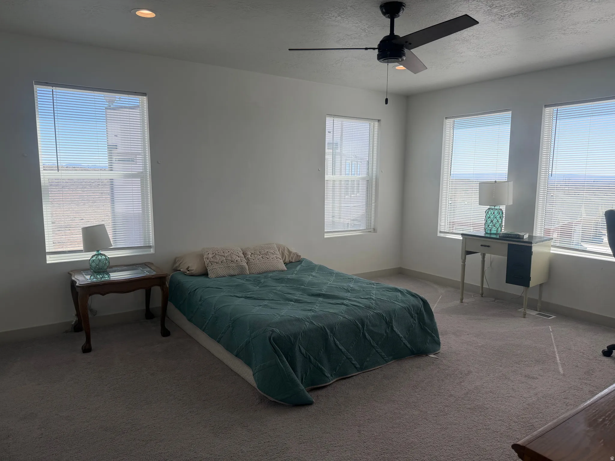 Bedroom featuring carpet, multiple windows, a ceiling fan, and a textured ceiling