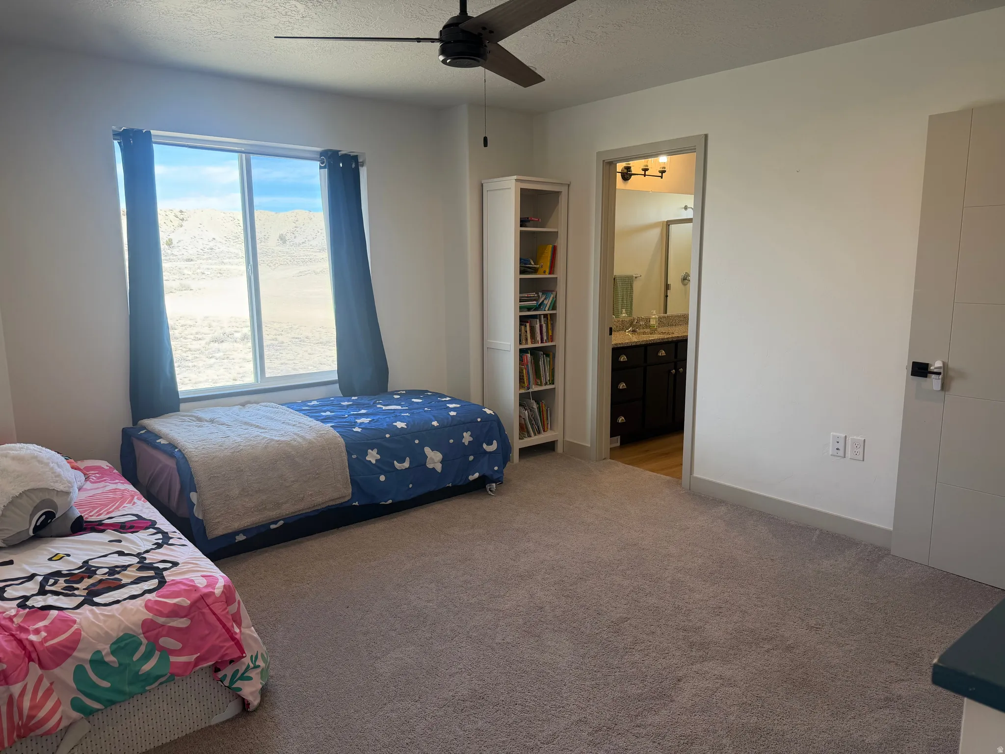 Bedroom with light carpet, ceiling fan, a textured ceiling, and ensuite bath