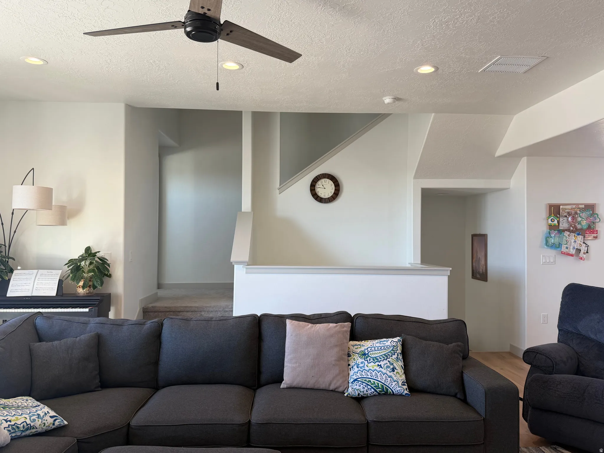 Living room with wood finished floors, recessed lighting, ceiling fan, and a textured ceiling