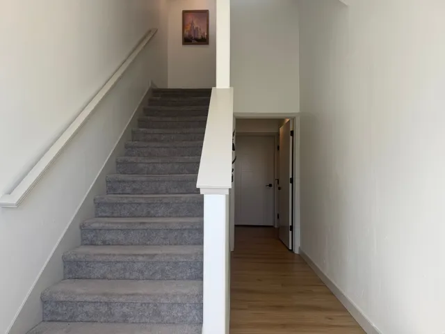Stairs with wood finished floors and a high ceiling