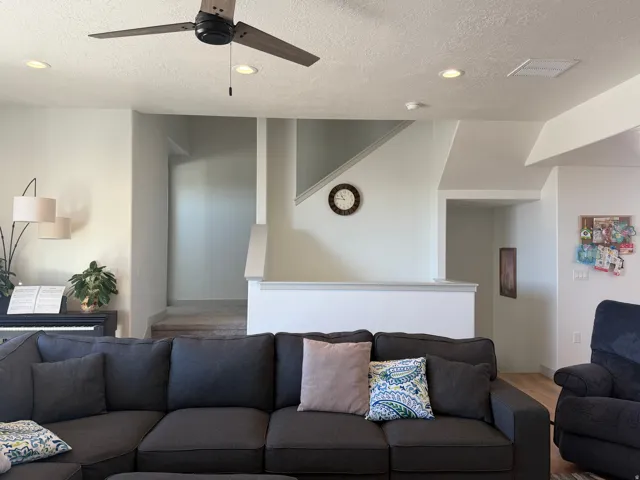 Living room with wood finished floors, recessed lighting, ceiling fan, and a textured ceiling