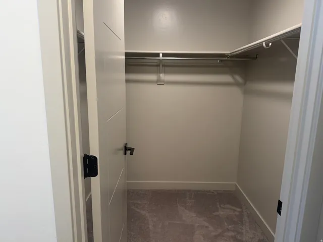 Walk in closet featuring dark colored carpet