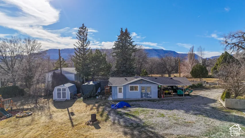 View of front of house featuring a mountain view, a fire pit, a patio area, and a storage shed