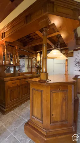 Indoor dry bar with wood finish cabinetry and light tile patterned floors