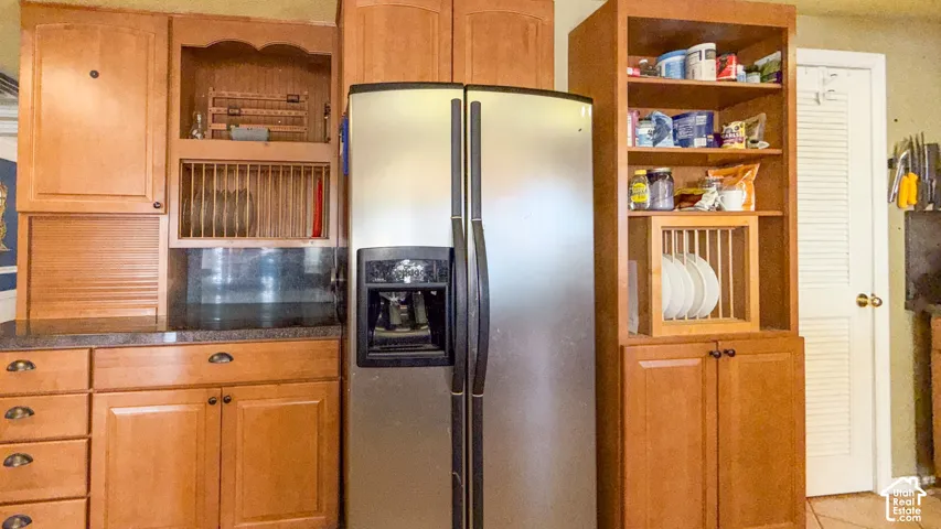 Kitchen featuring stainless steel fridge, wood finish cabinets, and open shelves
