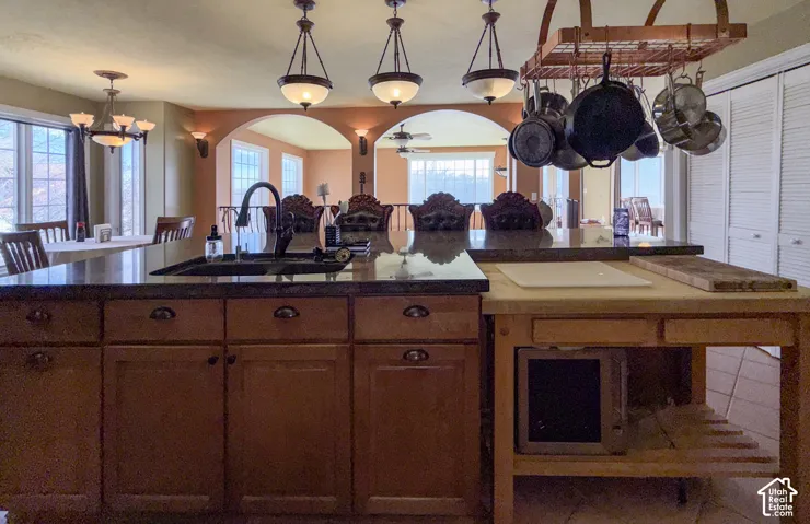 Kitchen with arched walkways, plenty of natural light, hanging lights, and wood finish cabinetry