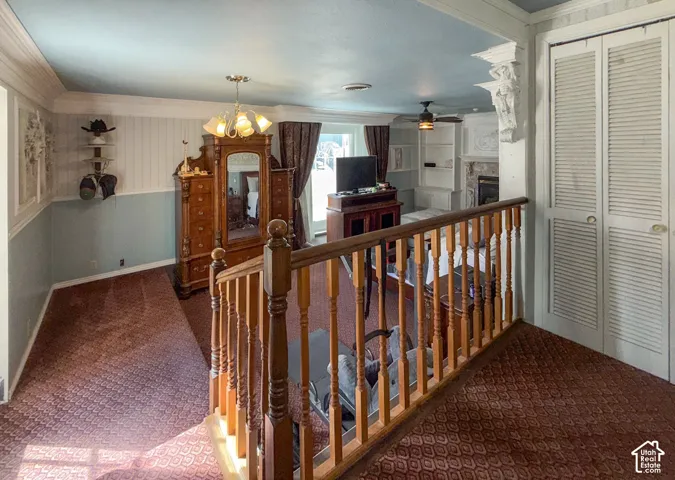 Corridor with carpet, ornamental molding, suspended lighting, and an upstairs landing