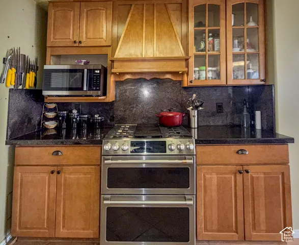 Kitchen featuring stainless steel appliances, dark stone countertops, tasteful backsplash, and wood finish cabinetry