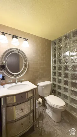 Bathroom with tile walls, vanity, and a textured ceiling