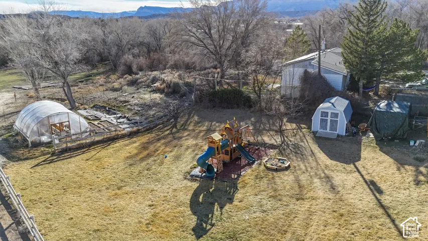 View of yard featuring an exterior structure, a storage unit, a playground (NOT INCLUDED), and a mountain view