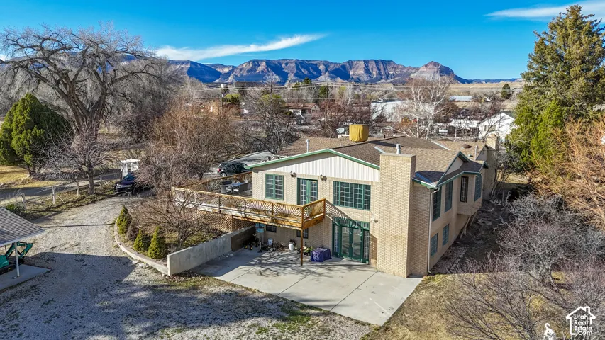 Back of property with a patio, a chimney, a deck with mountain view, and brick siding