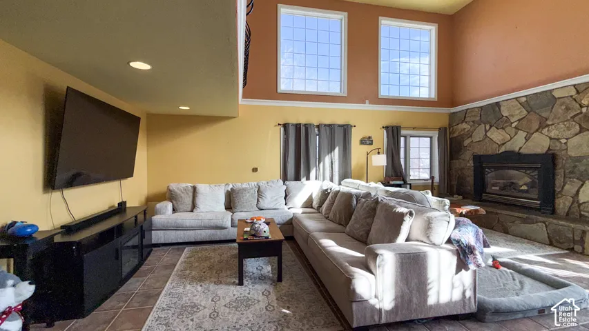 Living room featuring a high ceiling, a fireplace, and tile patterned floors