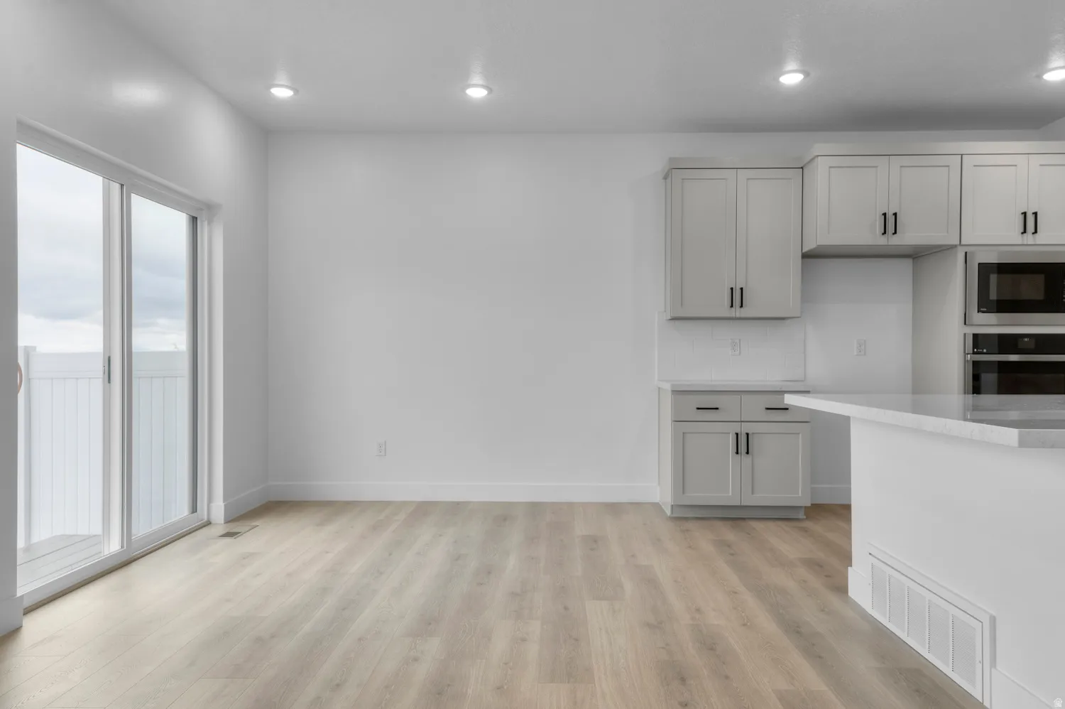 Kitchen featuring light stone counters, recessed lighting, stainless steel appliances, light wood-style floors, and gray cabinets