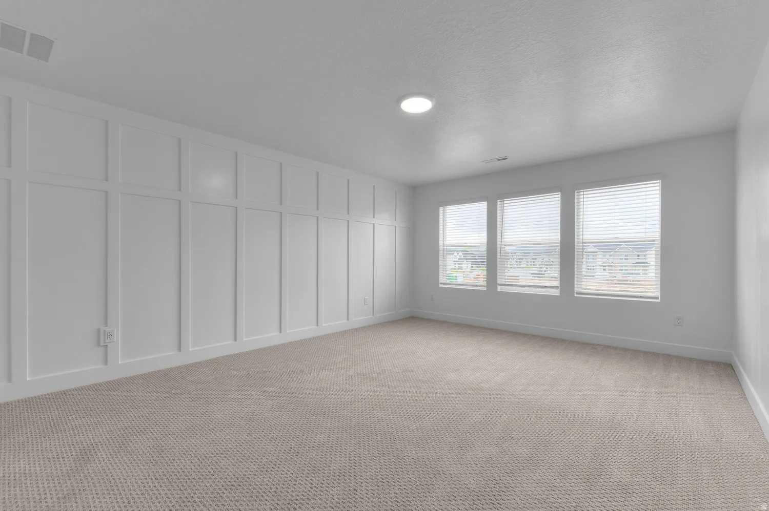 Empty room featuring a decorative wall and light carpet