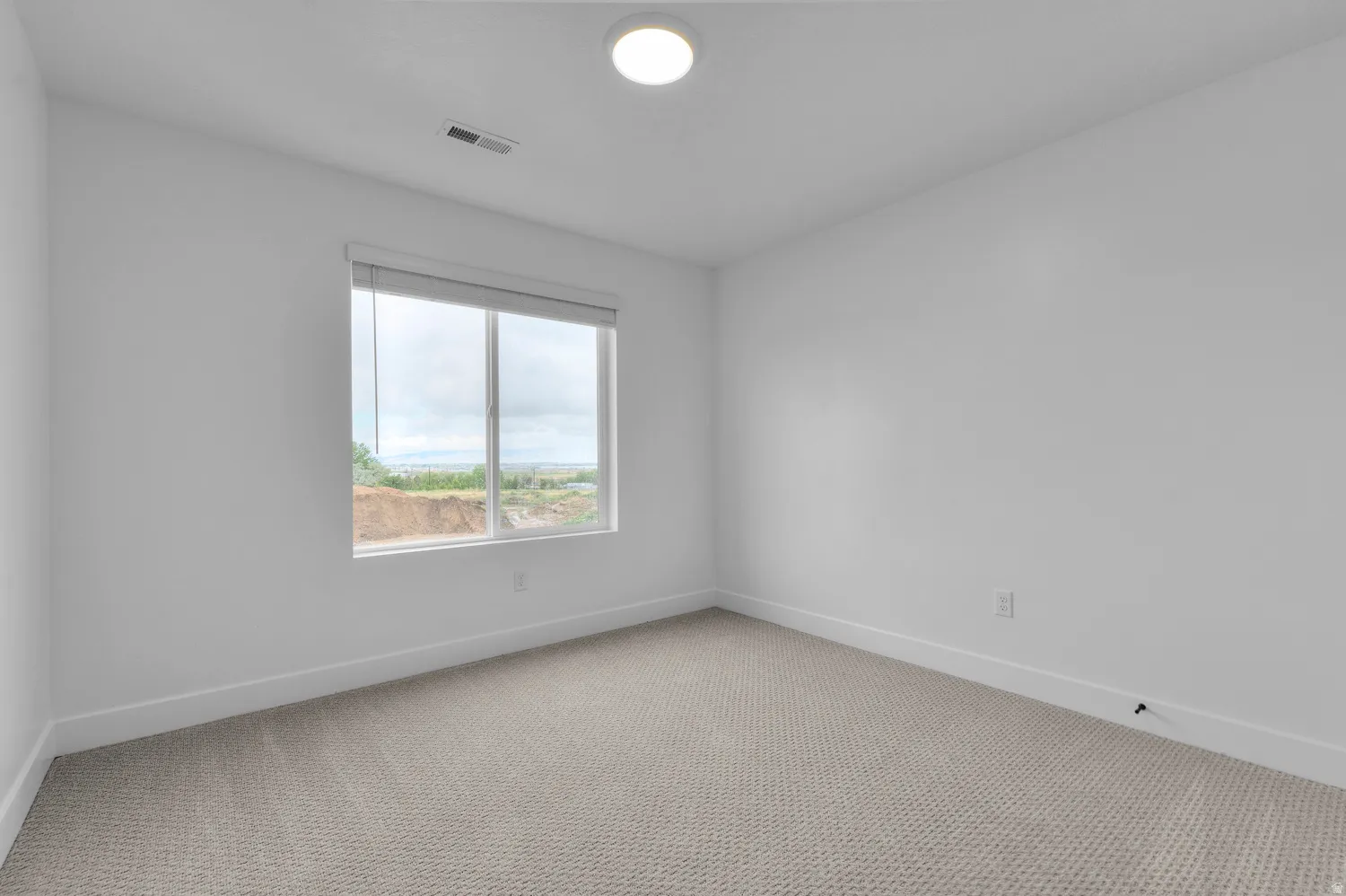 Empty room featuring baseboards and light colored carpet