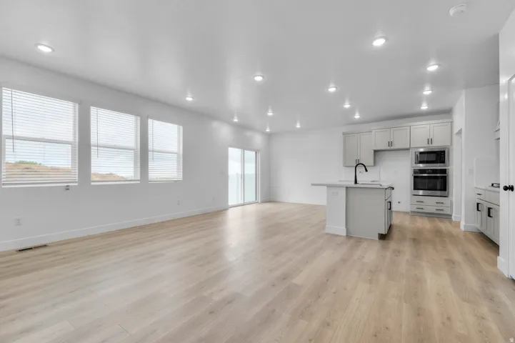 Kitchen featuring an island with sink, open floor plan, stainless steel appliances, light wood-style flooring, and recessed lighting