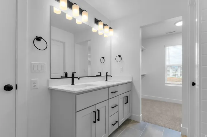 Full bathroom featuring double vanity, light tile patterned floors, and light colored carpet
