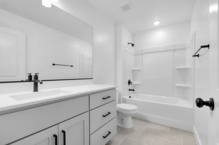 Bathroom with vanity, tub / shower combination, and light tile patterned floors