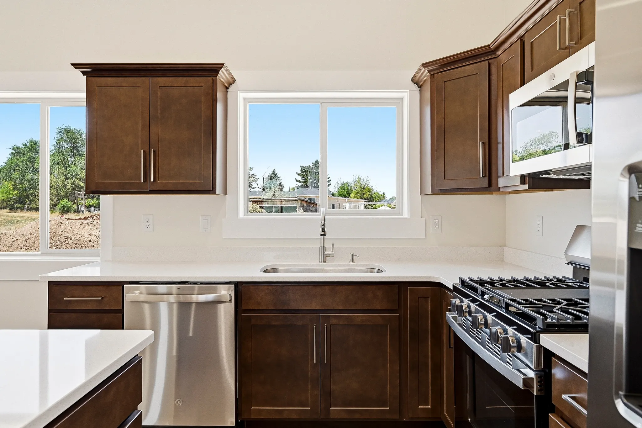 Kitchen featuring dark wood cabinetry, stainless steel appliances, a gas range, and white countertops