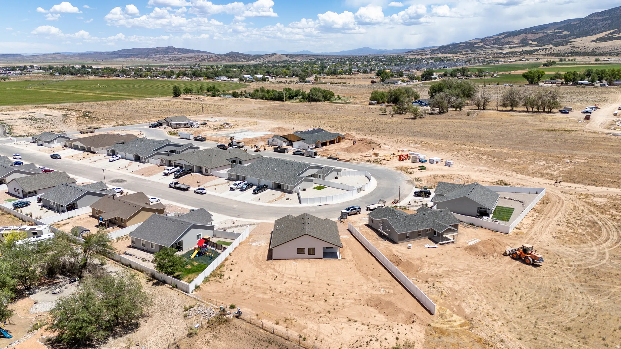 Aerial presentation of new construction homes with partial fencing and surrounding undeveloped land